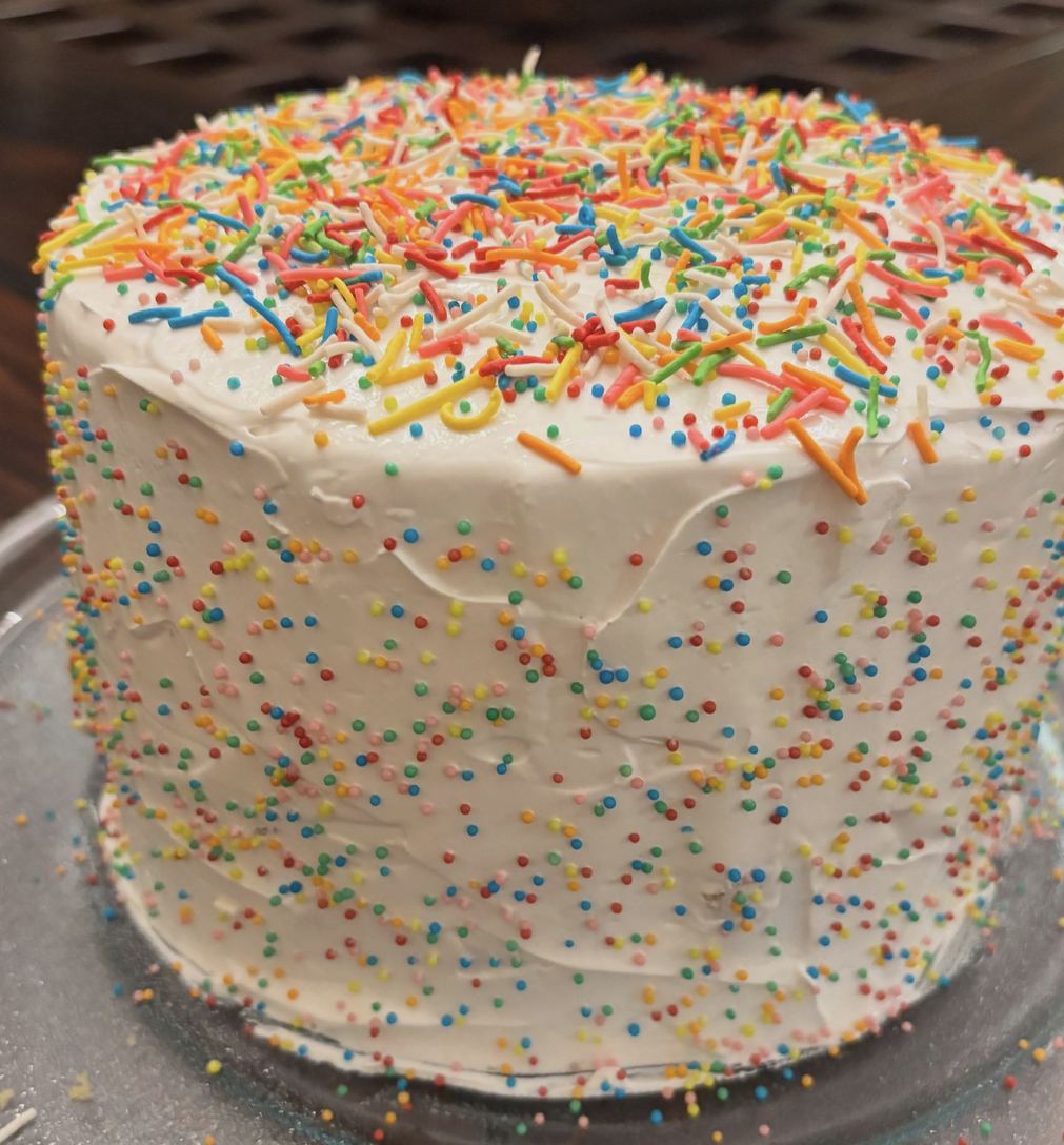 Pastel de confeti cubierto de betún blanco y chispas de colores